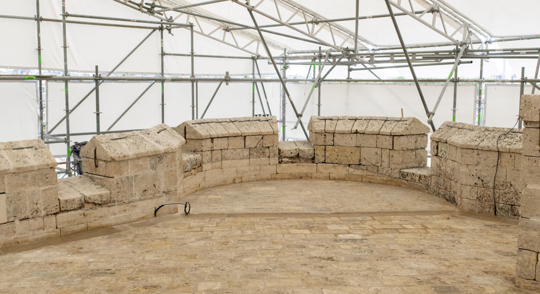 Vestiges archéologiques en pierres sous une structure de chantier temporaire au Donjon de Niort