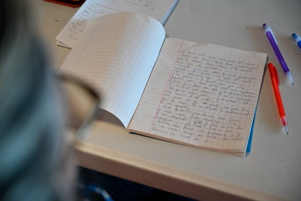 Carnet ouvert couvert d’écriture manuscrite, posé sur une table avec des stylos